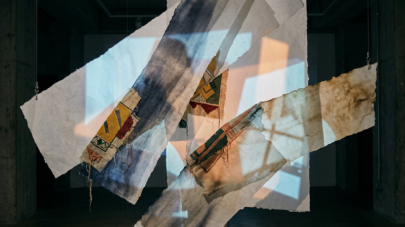 Abstract contemporary illustration of layered translucent textiles and archival photographs projected onto a glass facade