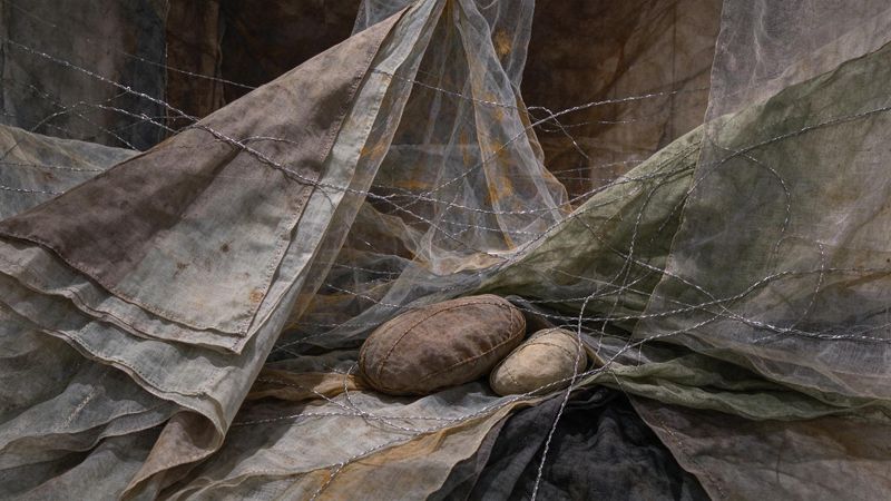 Abstract contemporary composition featuring layered translucent textiles and metallic threads arranged in organic formations