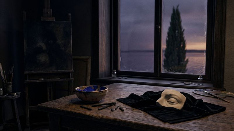 Dim fin-de-siècle studio with cypress silhouette beyond a tall window, charcoal sticks, gold pigment bowl and draped dark cloth on an oak table.